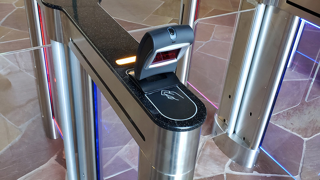 Biometric hand scanner mounted on a secure lobby entry turnstile